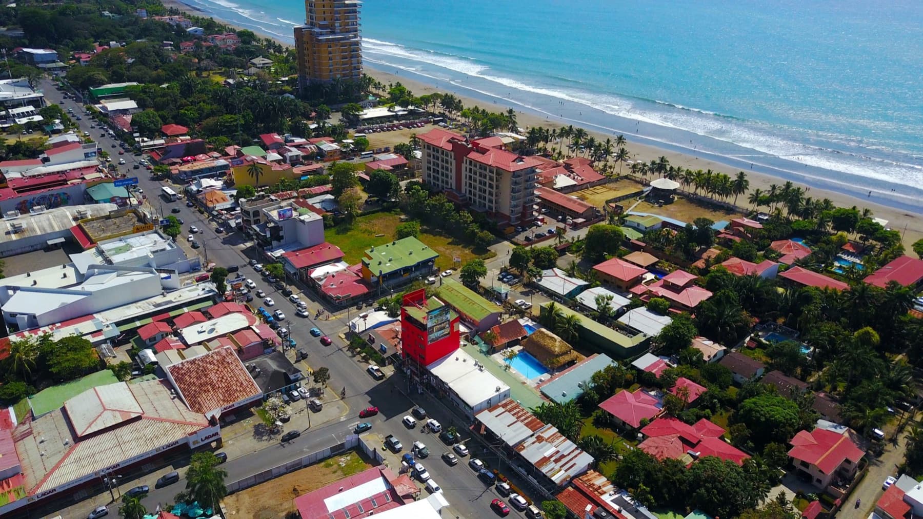 Aerial view of central Jacó, showing the dense grid of buildings and businesses between Avenida Pastor Díaz and the beach.